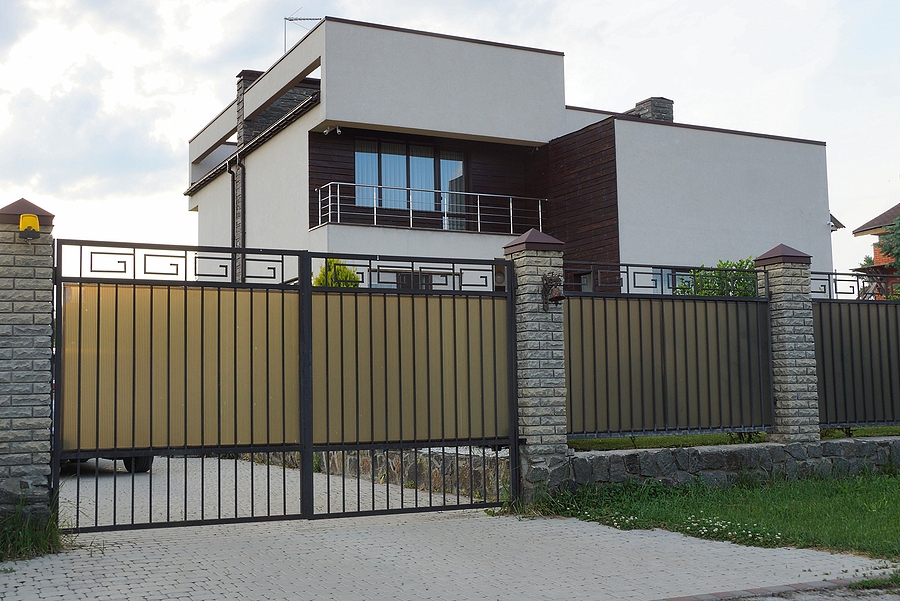 gray metal gate and fence in front of a private house with a balcony